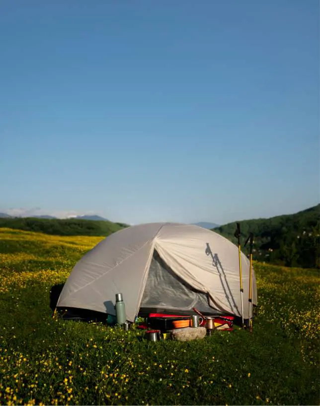 Lightweight orange camping tent pitched in an open field